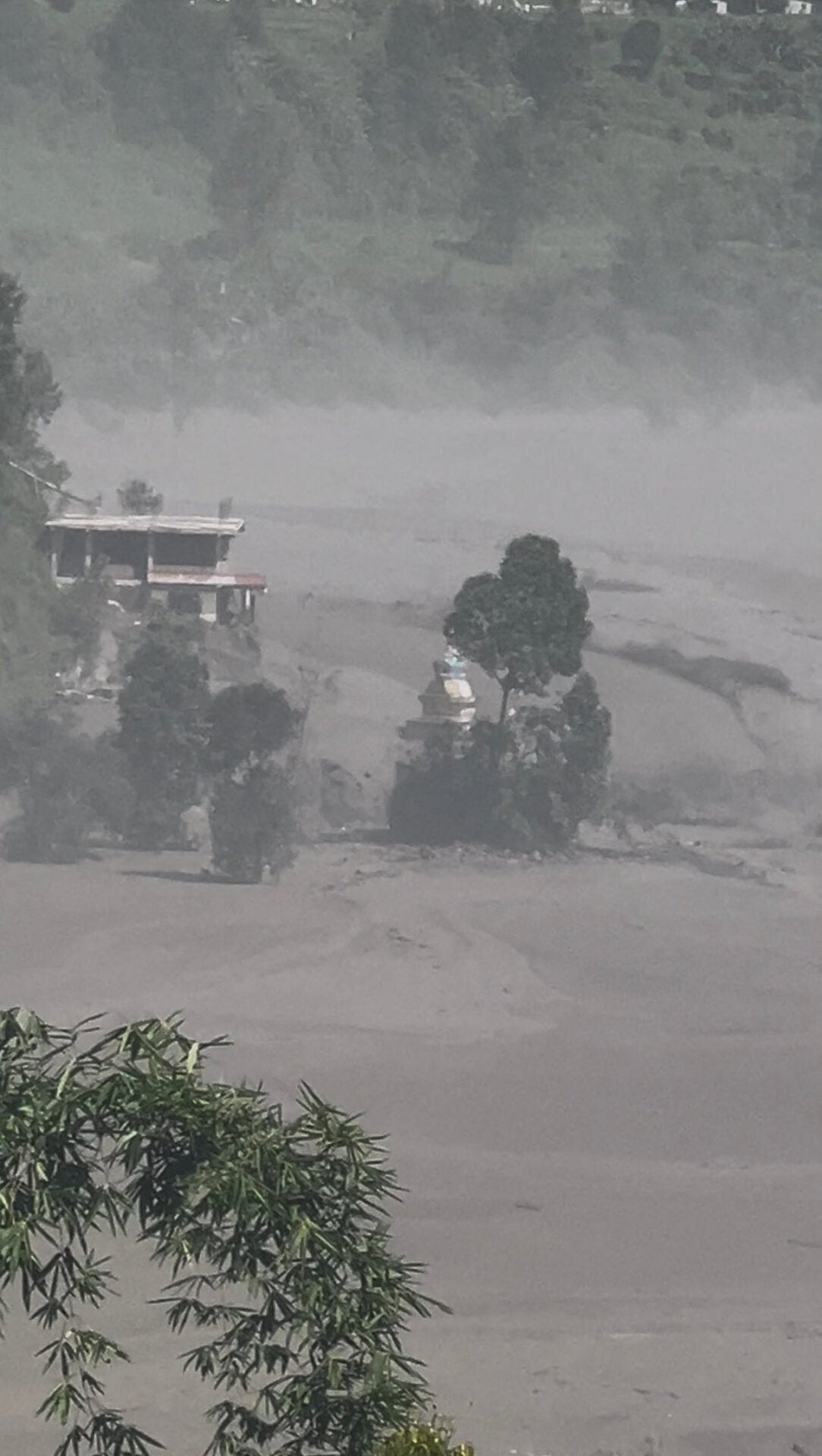 Partially submerged buildings along the riverbank due to a flash flood in Nuwakot district