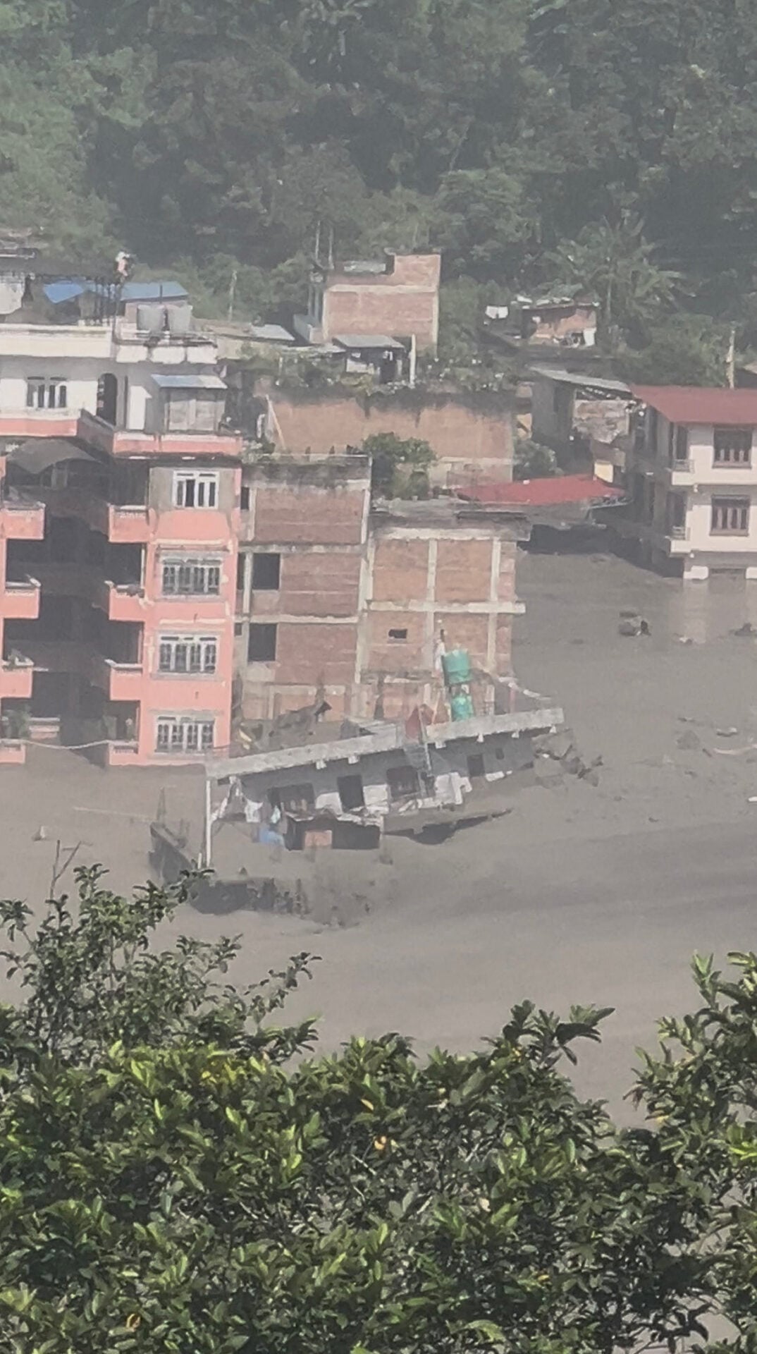 Partially submerged buildings along the riverbank due to a flash flood in Nuwakot district