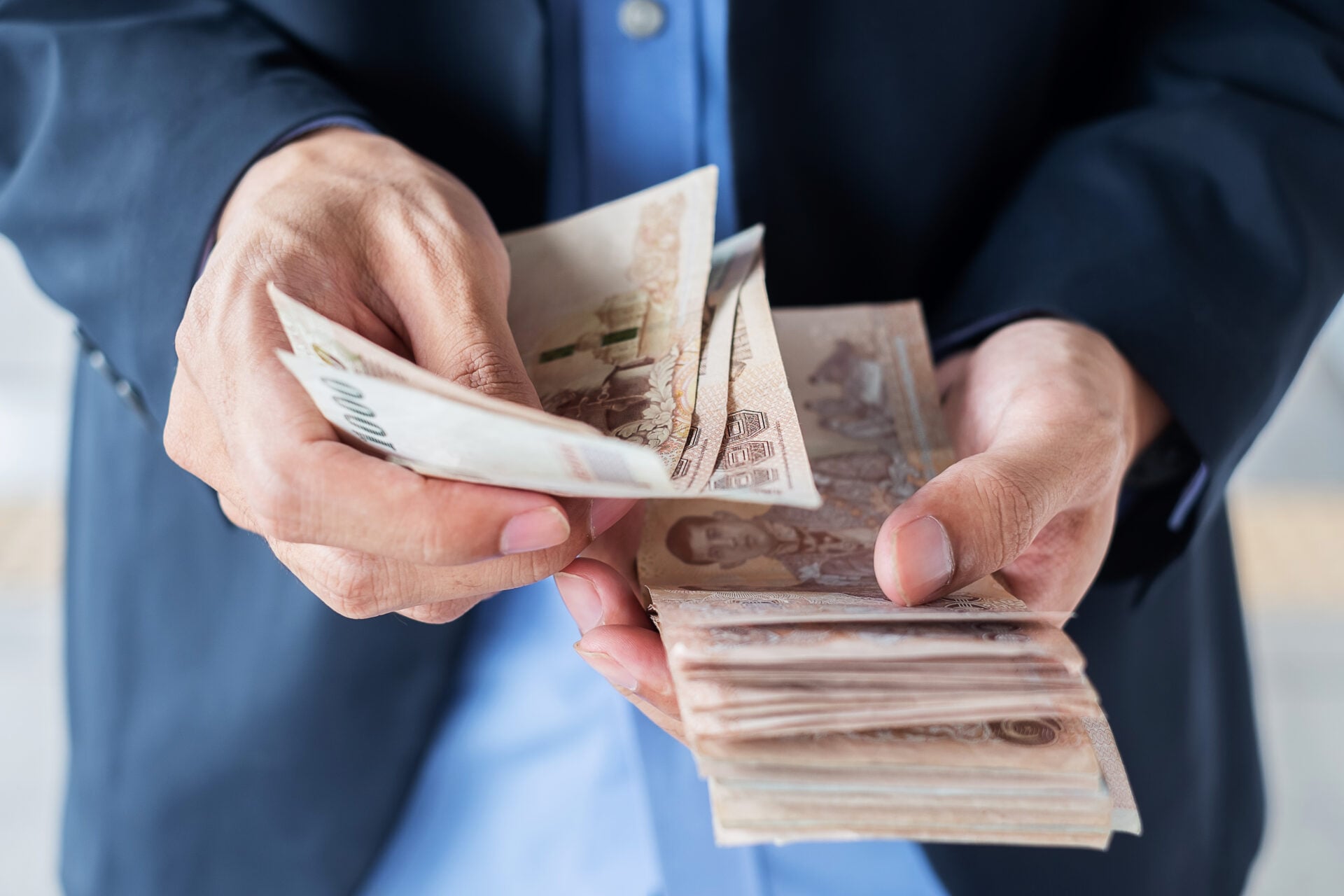 Businessman hand holding Thai Baht banknote stack. business, mon
