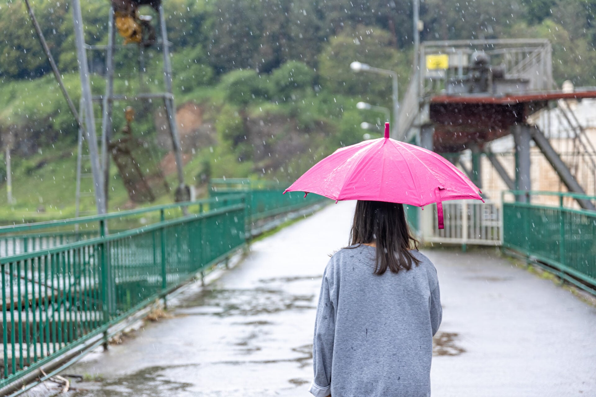 Back view of a girl under an umbrella on a walk in the rain.
